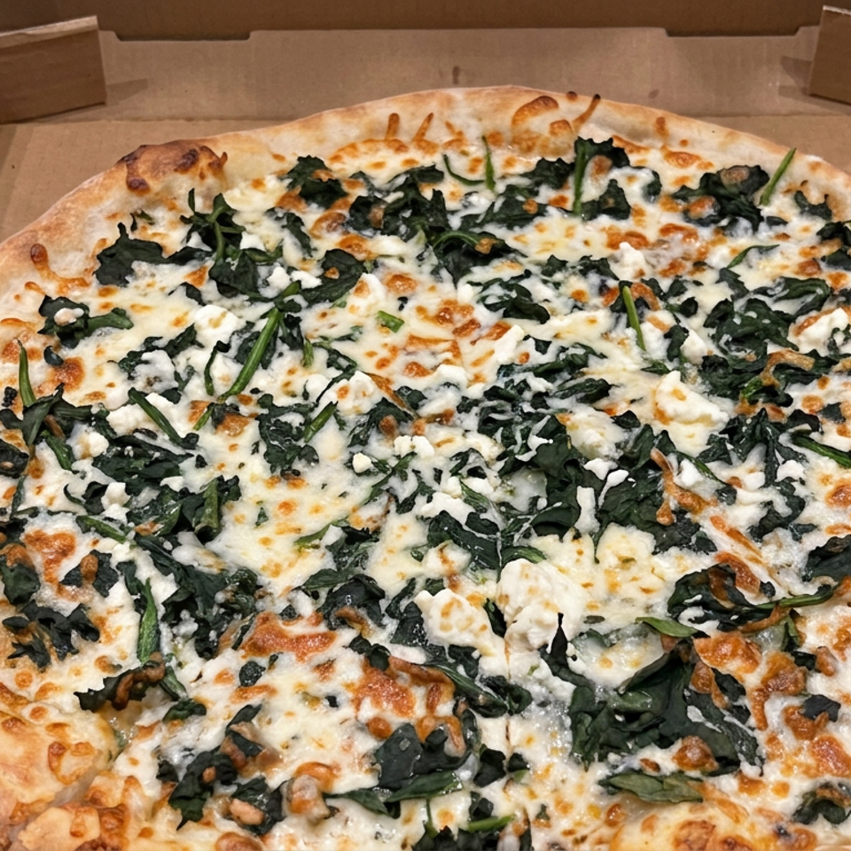 Large spinach and feta pizza with melted mozzarella in an open cardboard box.